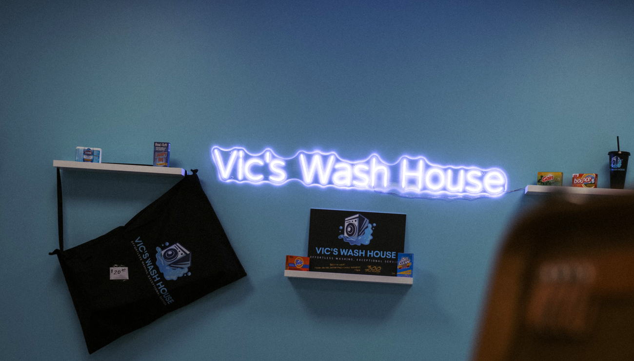 The Vic's Wash House neon sign on the wall inside the store